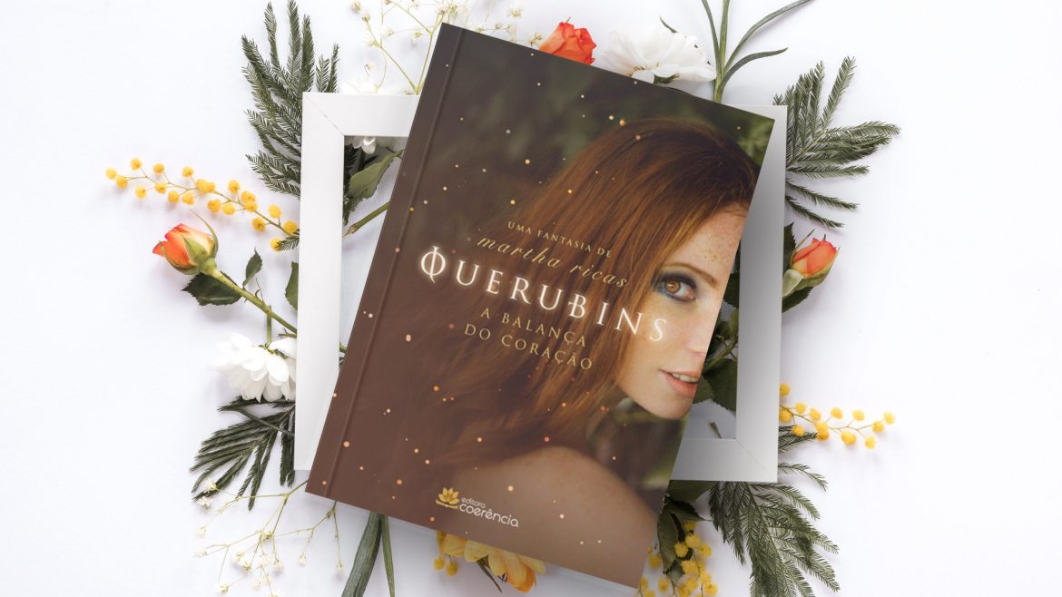 Livro "Querubins" em cima de um quadro com folhas e flores
